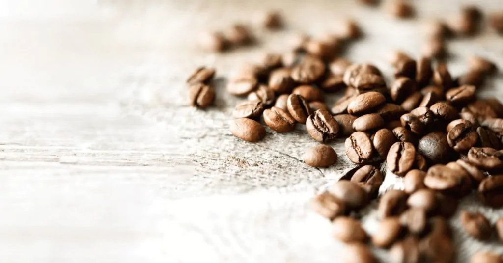 some coffee beans on white wood