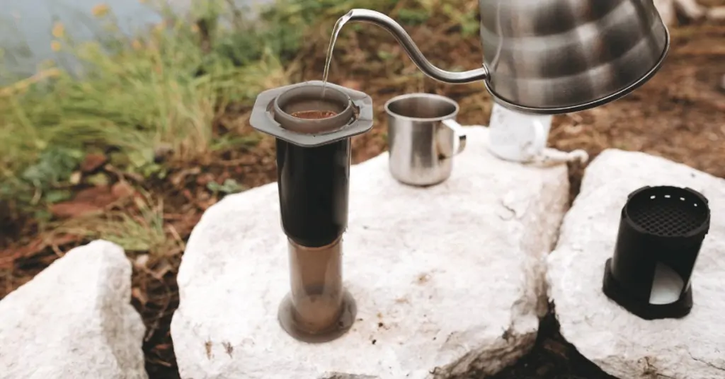 person brewing aeropress coffee outside