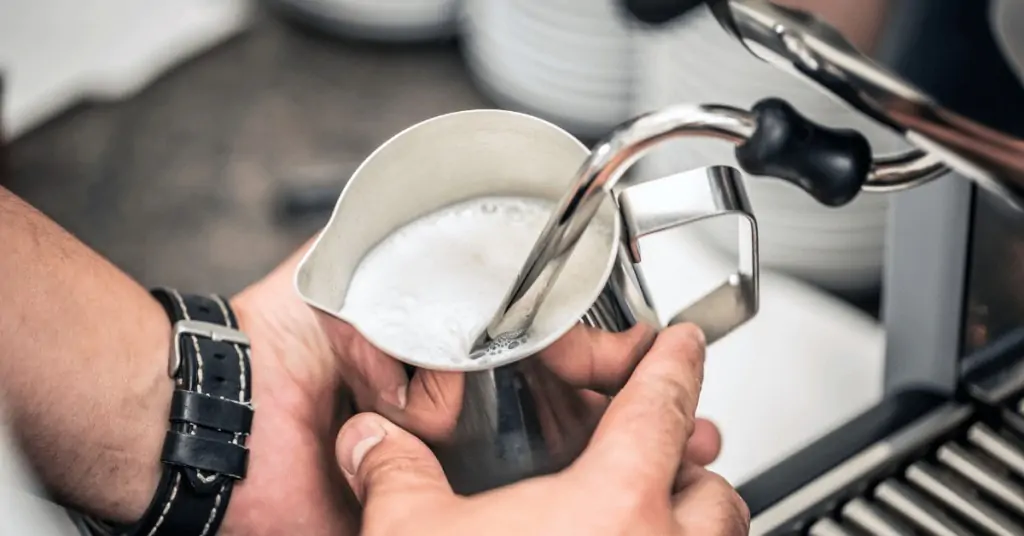 person steaming milk in a pitcher