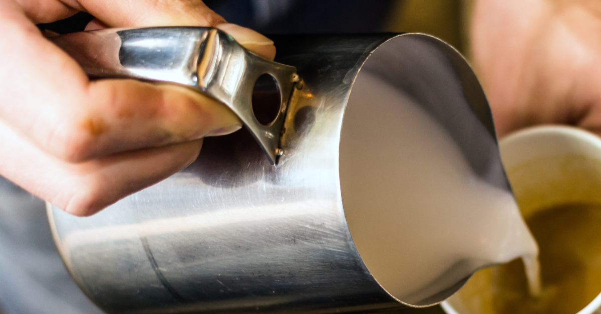 barista pouring milk into coffee