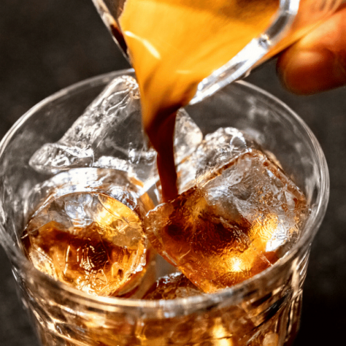 pouring coffee on ice cubes in glass