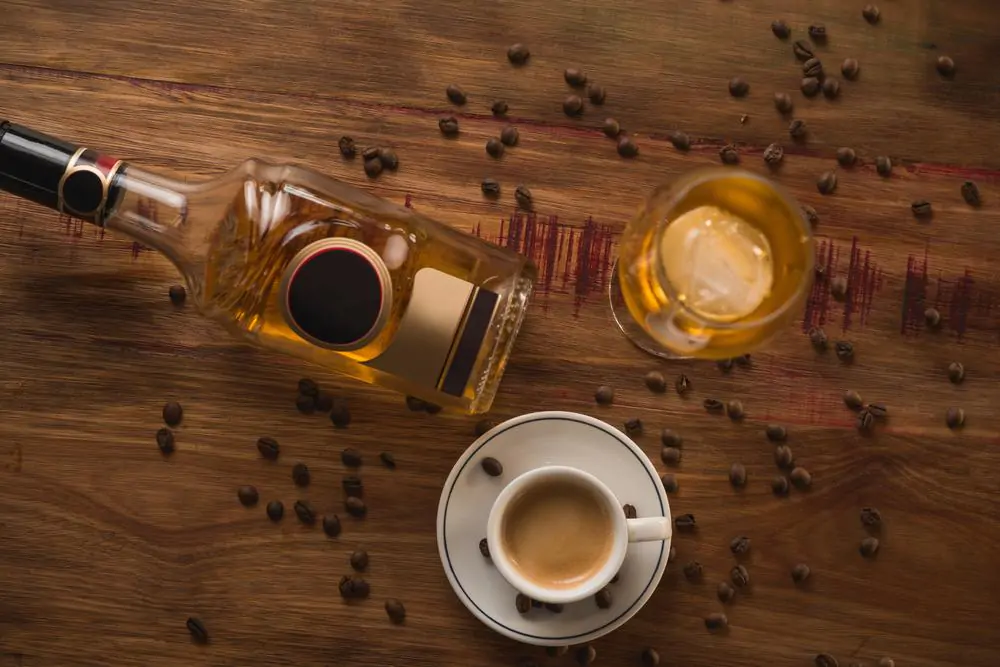 Carajillo cocktail, Spanish drink with 43 and coffee, with wooden table in the background